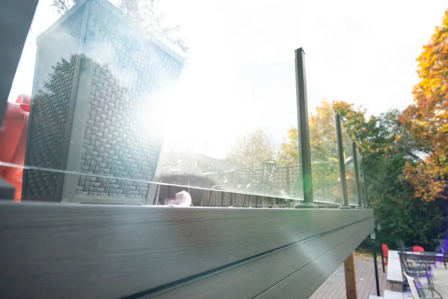 Close view of clear glass railing panels held between dark posts on a Toronto deck