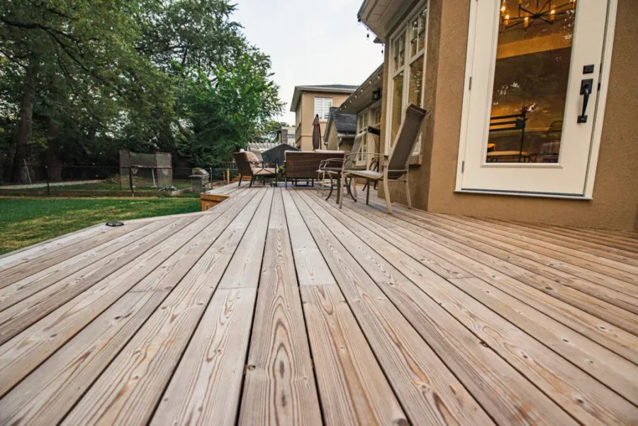 Close view of wood deck grain and board gaps beside a garden-facing door