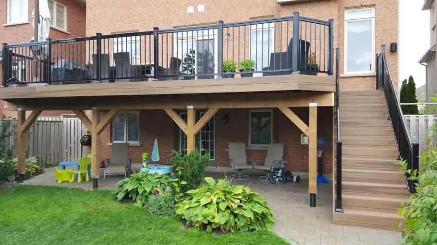 Framing of an elevated backyard deck under construction, showing joists, beams and open ventilation below the deck surface